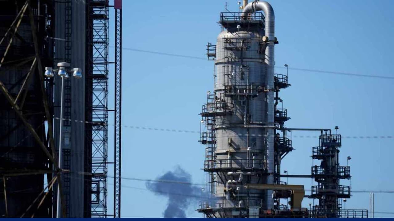 Industrial oil refinery tower with pipes against clear sky