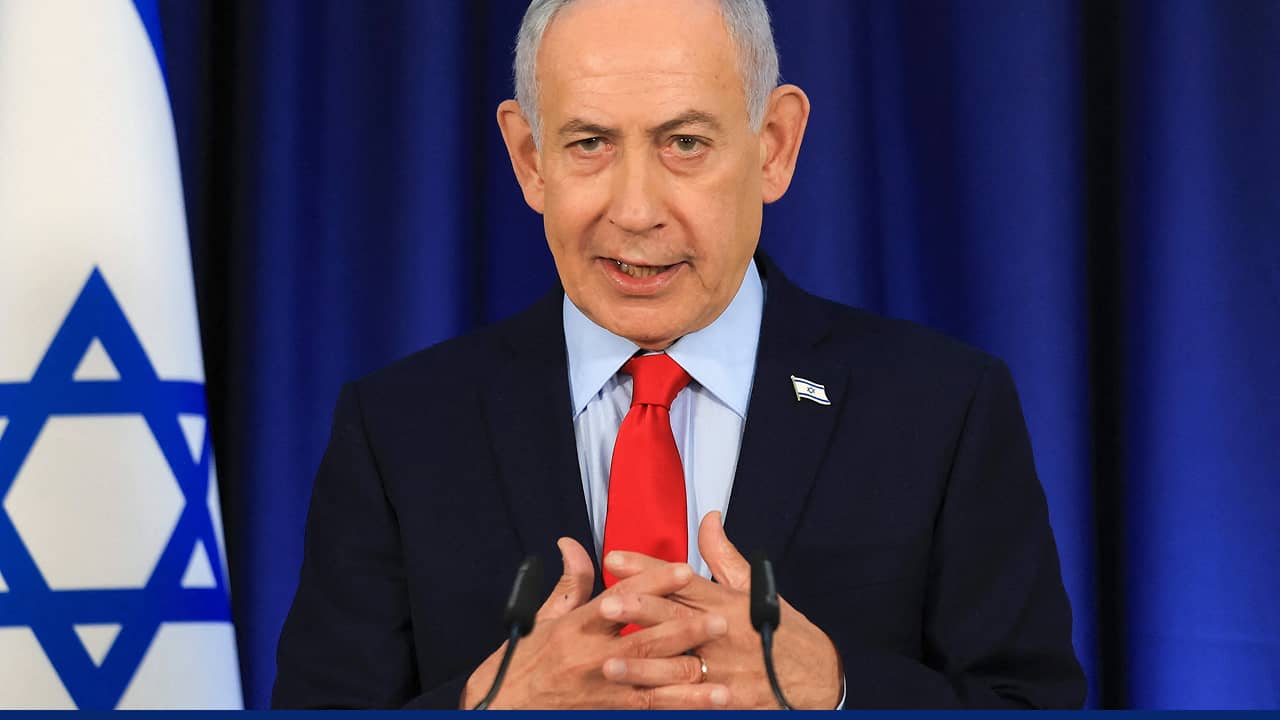 Benjamin Netanyahu delivers a statement during a press briefing, with the Israeli flag visible in the background.