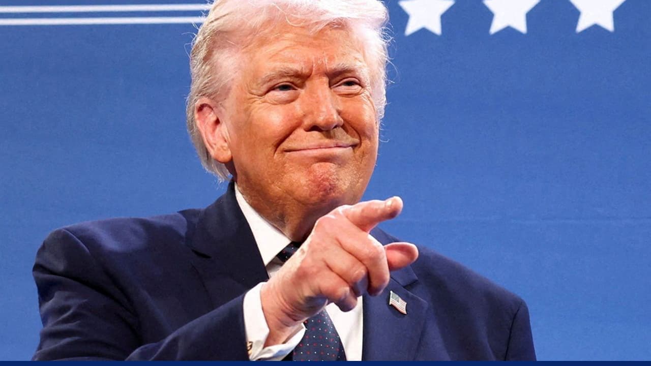 Donald Trump pointing during speech against blue star background