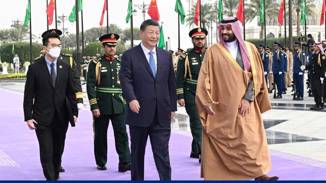 Chinese President Xi Jinping walks alongside Saudi Crown Prince Mohammed bin Salman during an official welcome ceremony, with military guards and national flags lined up in the background.