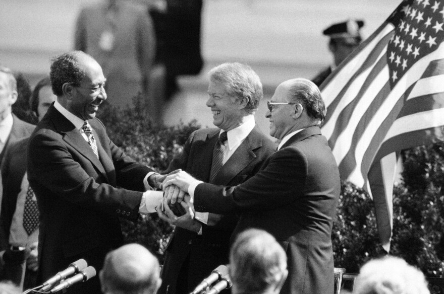 Egyptian President Anwar Sadat, left, President Jimmy Carter, center, and Israeli Prime Minister Menachem Begin clasp hands to symbolize their agreement after signing the Middle East Peace Treaty at the White House in Washington, March 27, 1979
